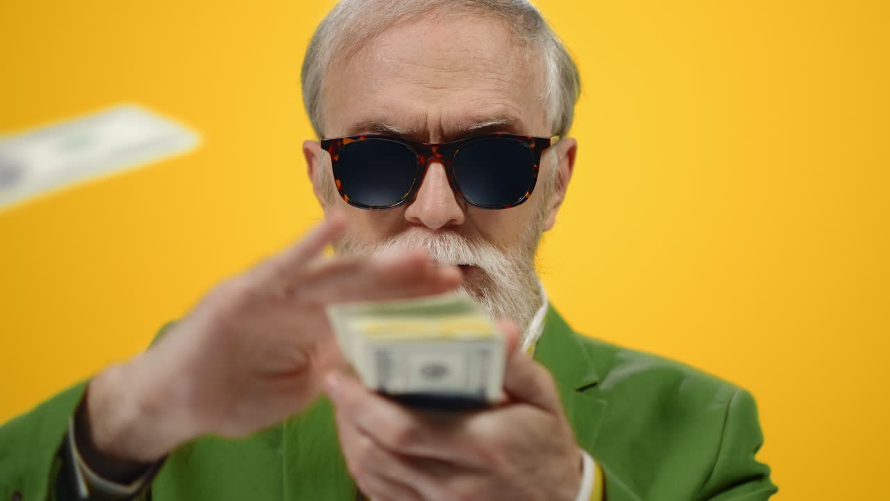 успешный мужчина рассыпает банкноты в студии, старик держит деньги внутри.