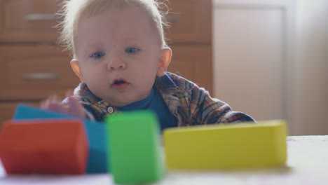 surprised baby looks at tower of color cubes on soft bed