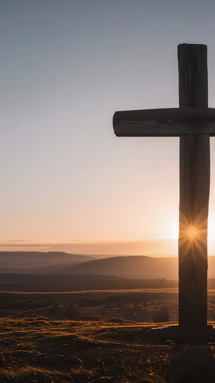 Vertical video: Emerging sun creating flare lighting rough wooden cross on hilltop, copy space
