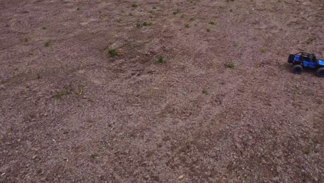 a small model rc truck competes in a hobby race, driving over rough terrain with an aerial view from a drone