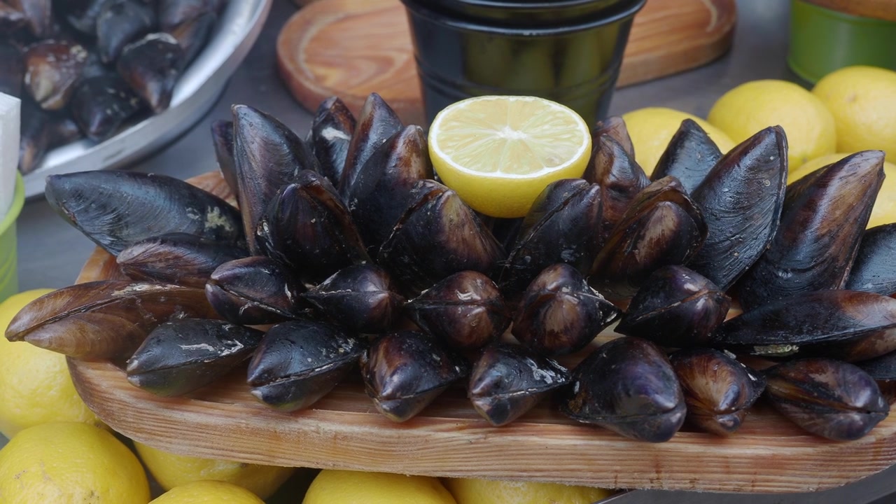 Nahaufnahme von gekochten Muscheln und Zitronen auf einer Holzplatte