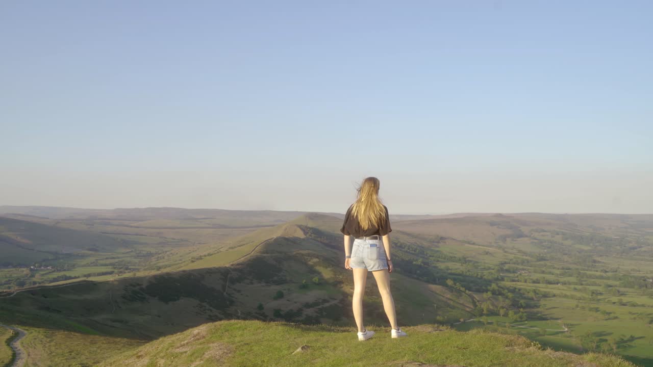 mam tor, castleton, peak district, 영국 꼭대기에 서서 푸른 언덕과 푸른 하늘을 감상하는 젊은 금발 여성의 안정된 샷