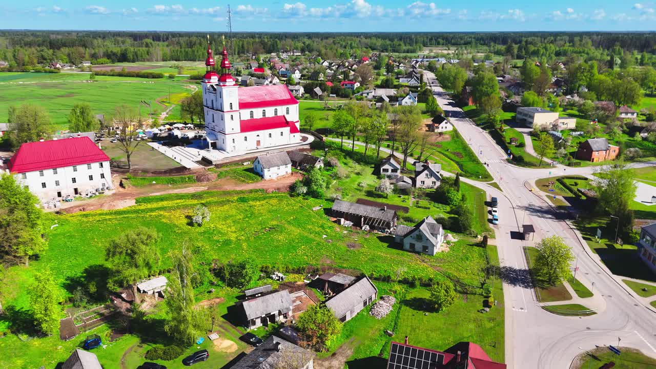 A small lithuanian town with a church and rural houses surrounded by green fields, aerial view