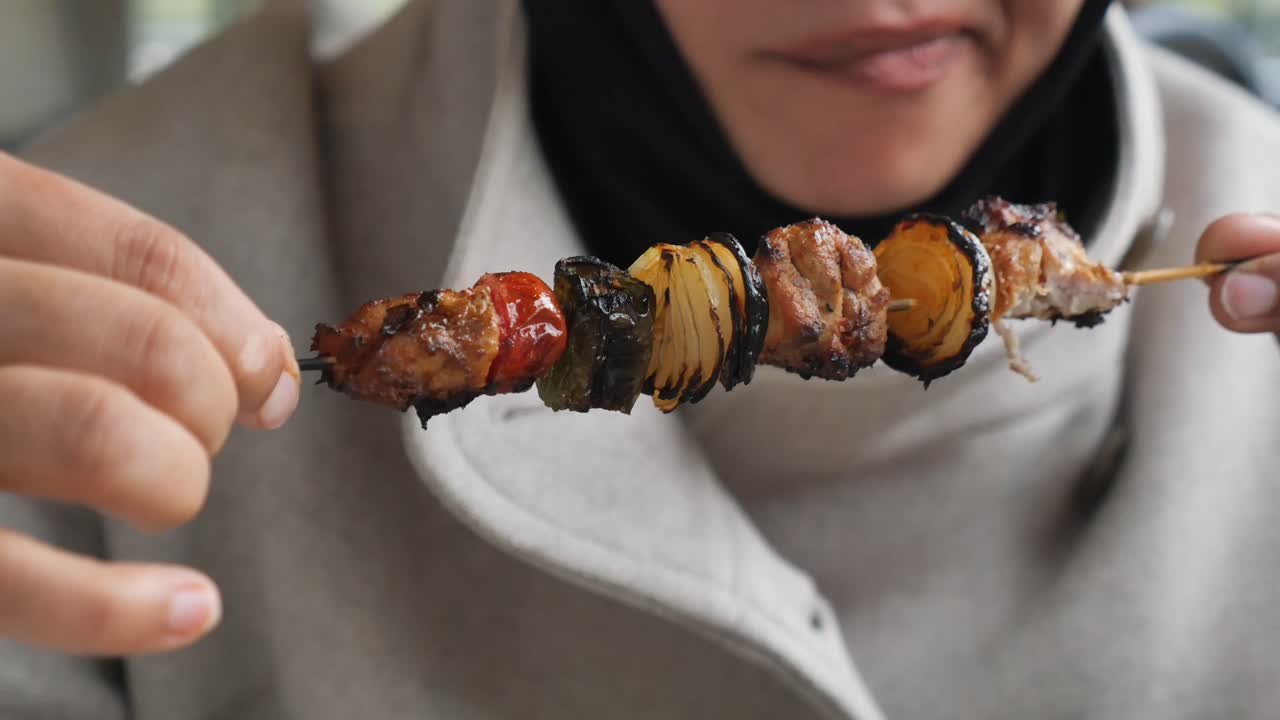 A person eating a kebab skewer