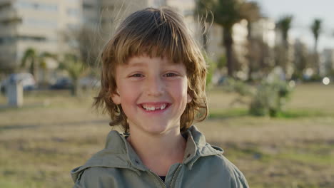 portrait of cute happy boy smiling cheerful at camera enjoying fun day on seaside park