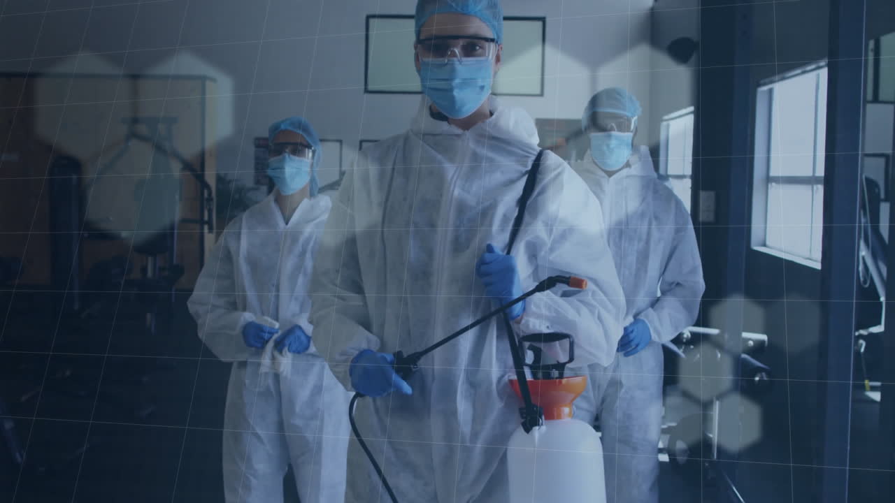 Sanitation team members spraying disinfectant wand in gym, showing digital grid hexagon overlay