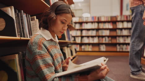 a young woman reading a book in the library