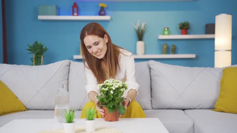 Young-woman-smelling-pot-flower-at-home.
