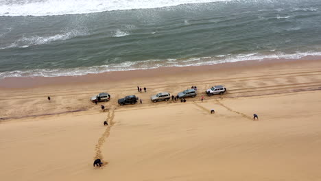 reveal-shot-of-cars-on-the-beach-next-to-a-huge-dune-in-the-Namib-desert