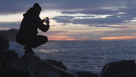 Tolle-Meereswellen-An-Der-Strandbucht,-Mann-Macht-Fotos,-Genießt-Die-Dämmerige-Aussicht-Zur-Blauen-Stunde