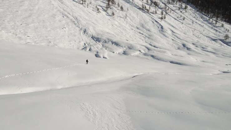 Un uomo fa trekking nel cuore delle montagne innevate italiane con le ciaspole.