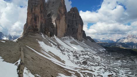 turistas caminando hacia las colinas cubiertas de nieve de tre cime di lavaredo en el parque nacional dolomiti