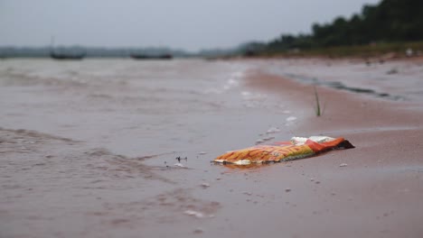 Müll-Und-Einwegplastik-Liegen-Am-Flussufer-Und-Werden-Von-Wellen-Im-Sand-Umspült