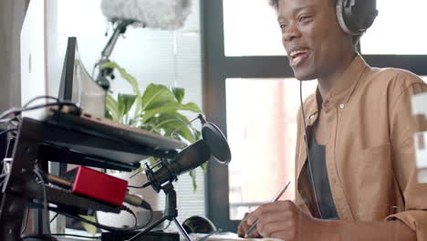 happy african american man in headphones making live podcast from home, copy space, slow motion