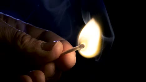 imágenes macro en cámara lenta de una vela blanca encendida por un fósforo sobre un fondo oscuro