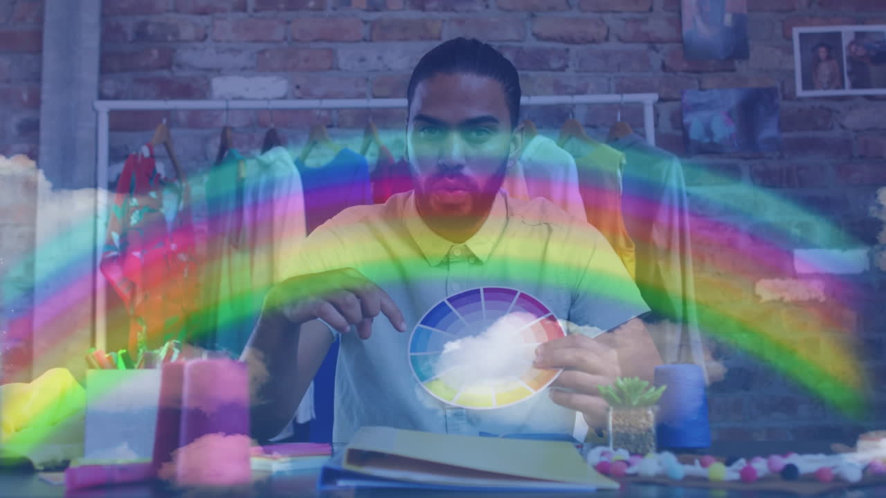 Rainbow light trails against african american male fashion designer holding a color pallete