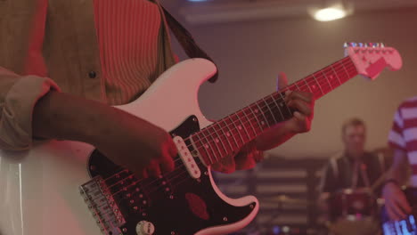 unrecognizable girl playing guitar during a band rehearsal in recording studio