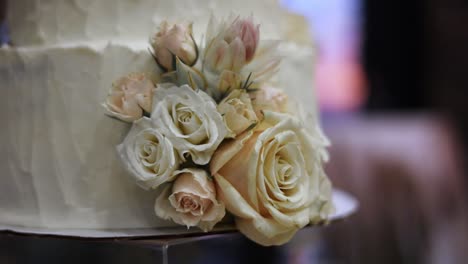 Close-up-of-Frosted-White-Wedding-Cake-Decorated-with-Floral-Bouquet-of-Pretty-Roses,-Dolly-Out