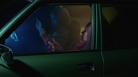 two women driving at night in a retro car