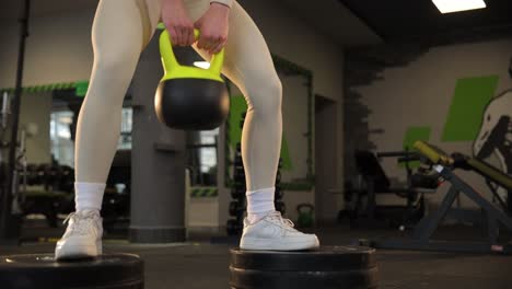 woman performing kettlebell squat in gym
