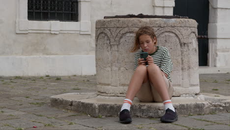 boy sitting on well and looking at phone