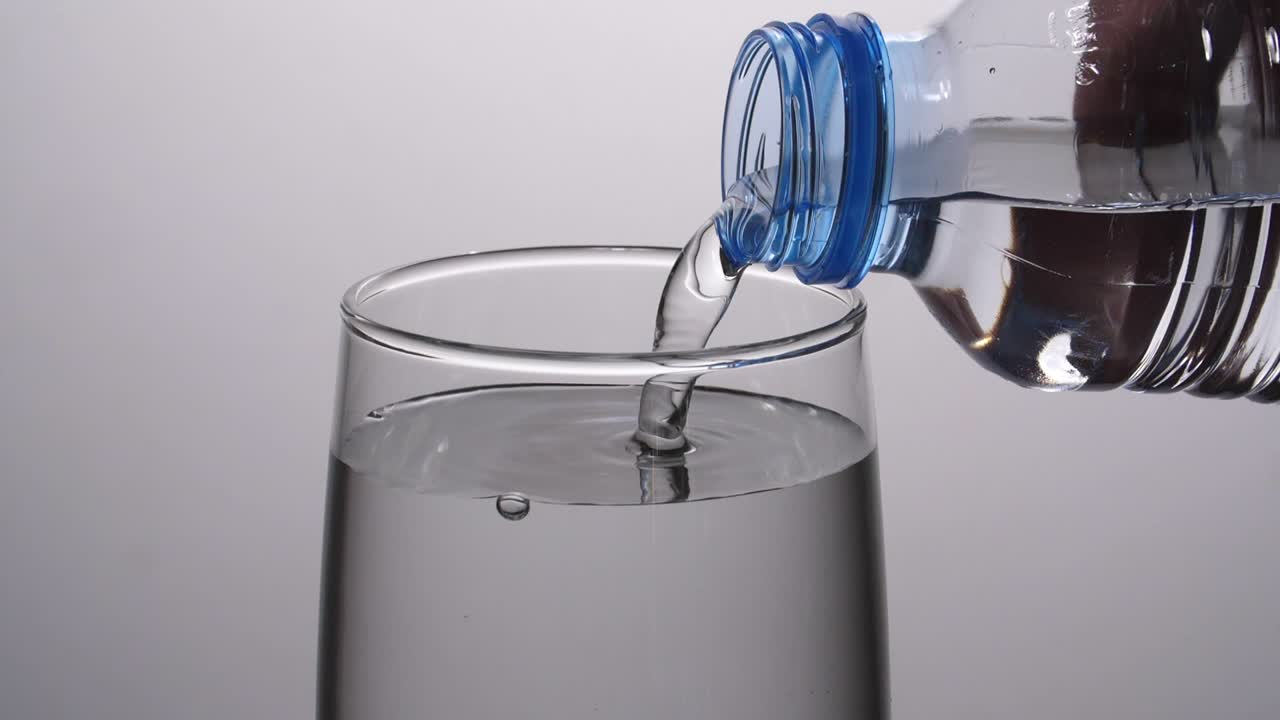 verter agua de una botella de plástico en un vaso