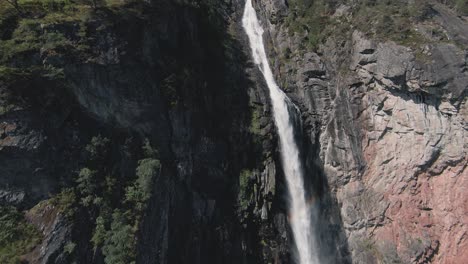 FPV-flying-up-streaming-waterfall-in-Norway,-cinematic-view