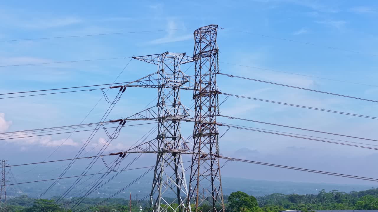 Electrical transmission towers with power lines stretching over countryside, representing modern energy supply, grid system, and industrial infrastructure