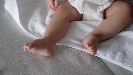 close up gentle parent hands lovingly holding baby's legs on soft towel