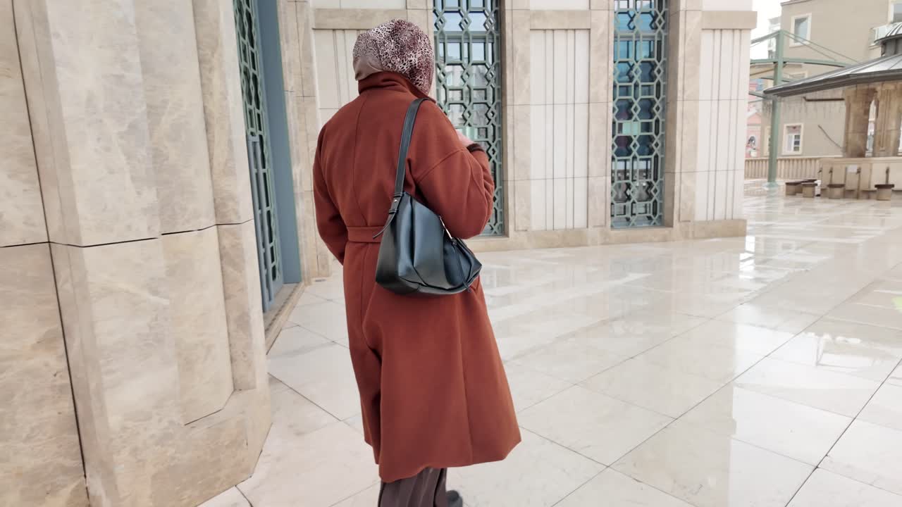 Woman in Hijab and Long Coat Walking in a Modern Urban Setting