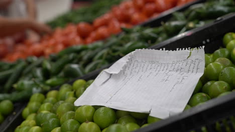 a paper shopping list on a pile of limes at a busy grocery store - isolated