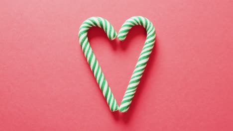 Video-of-two-green-christmas-canes-over-bright-red-background