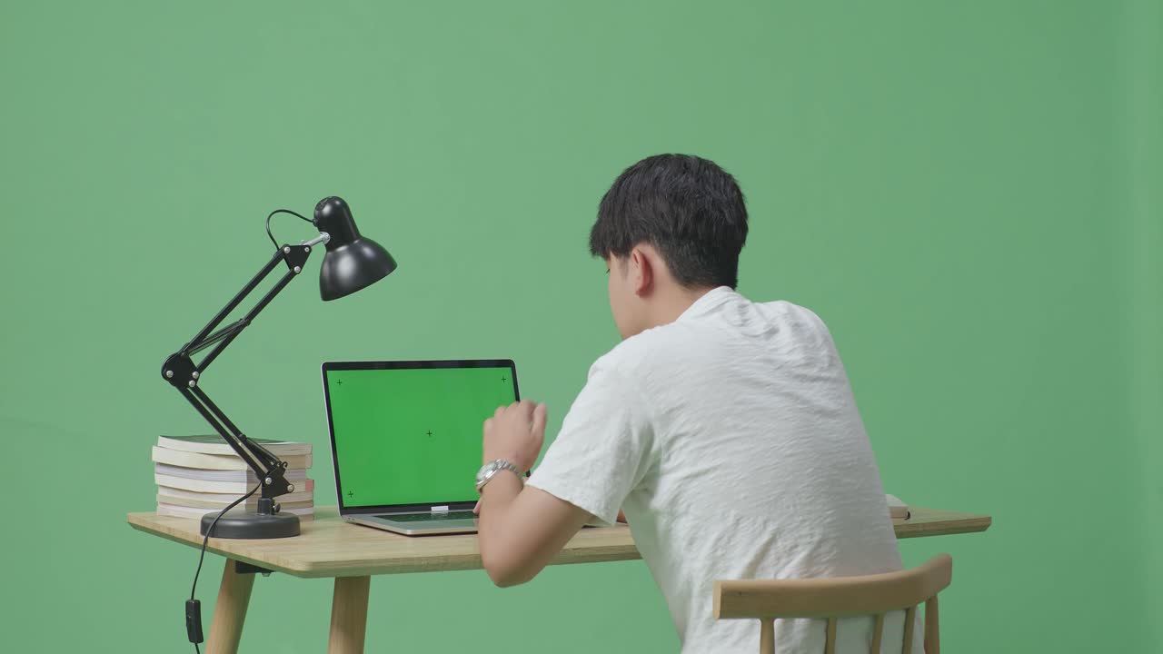 젊은 남성이 집에서 녹색 화면 배경에서 녹색 스크린 노트북에서 타이핑하는 데 피곤합니다.