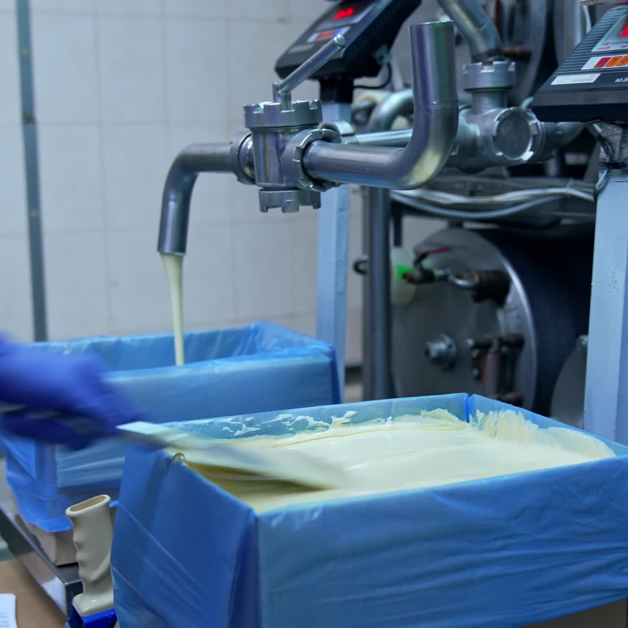 Liquid butter is pouring from the pipe into the container. Factory for the production of butter. Automated line. Food production