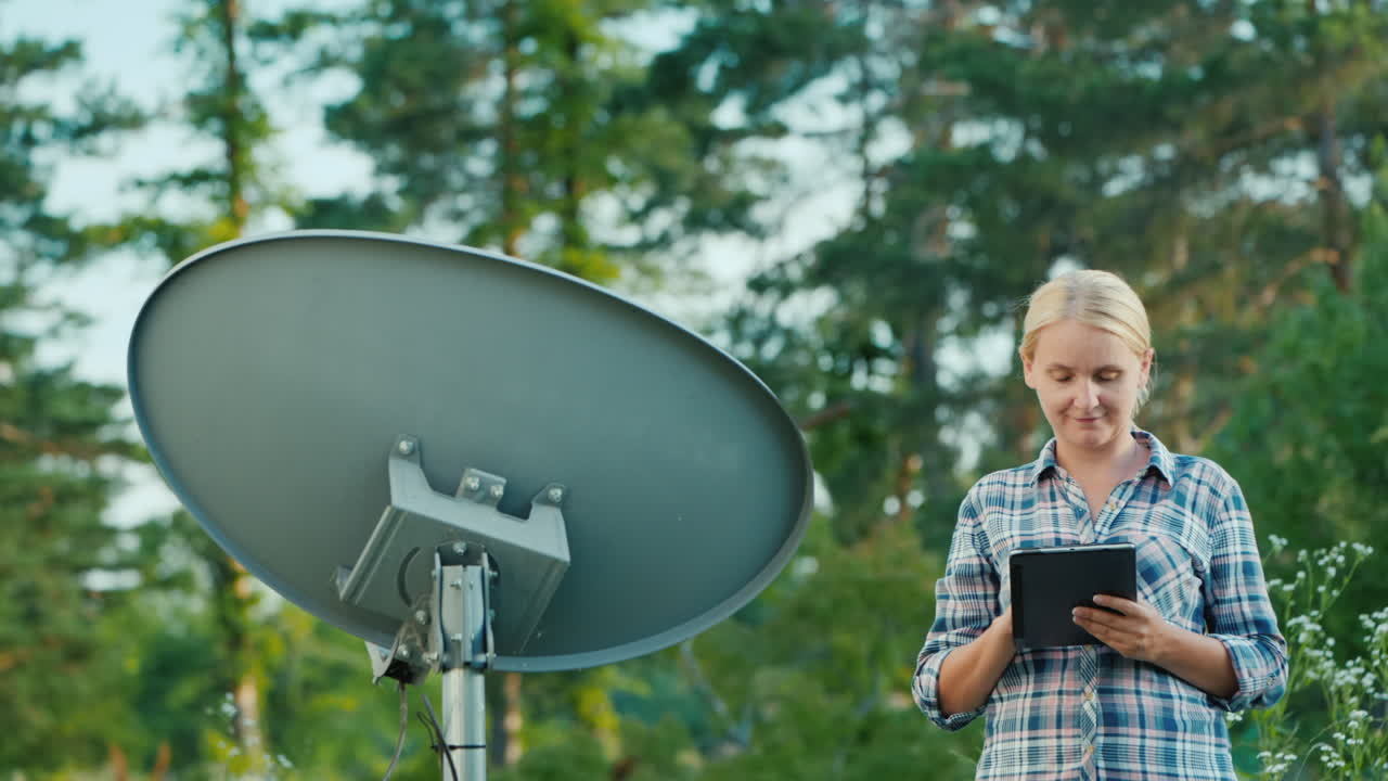 mujer sintoniza antenas parabólicas al aire libre utiliza tablet