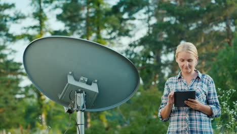 Frau-Stimmt-Satellitenschüsseln-Im-Freien-Mit-Tablet-Ab