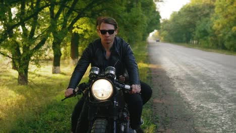 Handsome-man-in-sunglasses-with-his-girlfriend-stopping-his-vintage-motorcycle-on-the-road-side