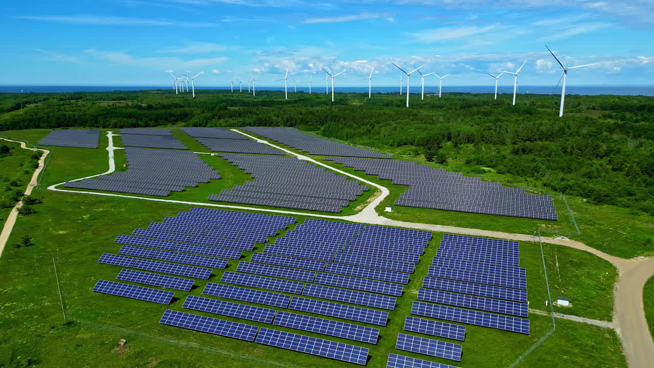 Drone aerial landscape of solar panel farm with wind turbines in background power energy generator industry sustainable renewables climate change