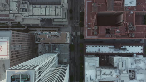 Slow-Aerial-Drone-View-of-City-Street-with-Skyscraper-Rooftops-and-Road-traffic,-Birds-Eye-Overhead-Top-Down-View-in-Daylight