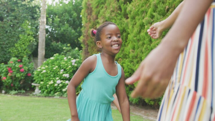 une mère afro-américaine embrassant ses deux filles souriantes dans le jardin