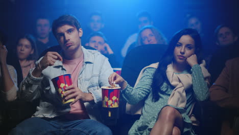 una pareja molesta comiendo palomitas de maíz en el cine.