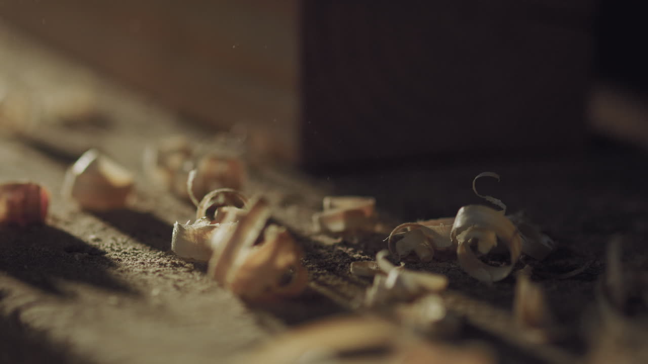 Wood chips scattered on a surface in a craft workshop, illuminated by warm, dim light.