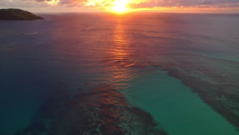 vibrant golden sunset over water and coral reef, yasawa, fiji, reveal shot