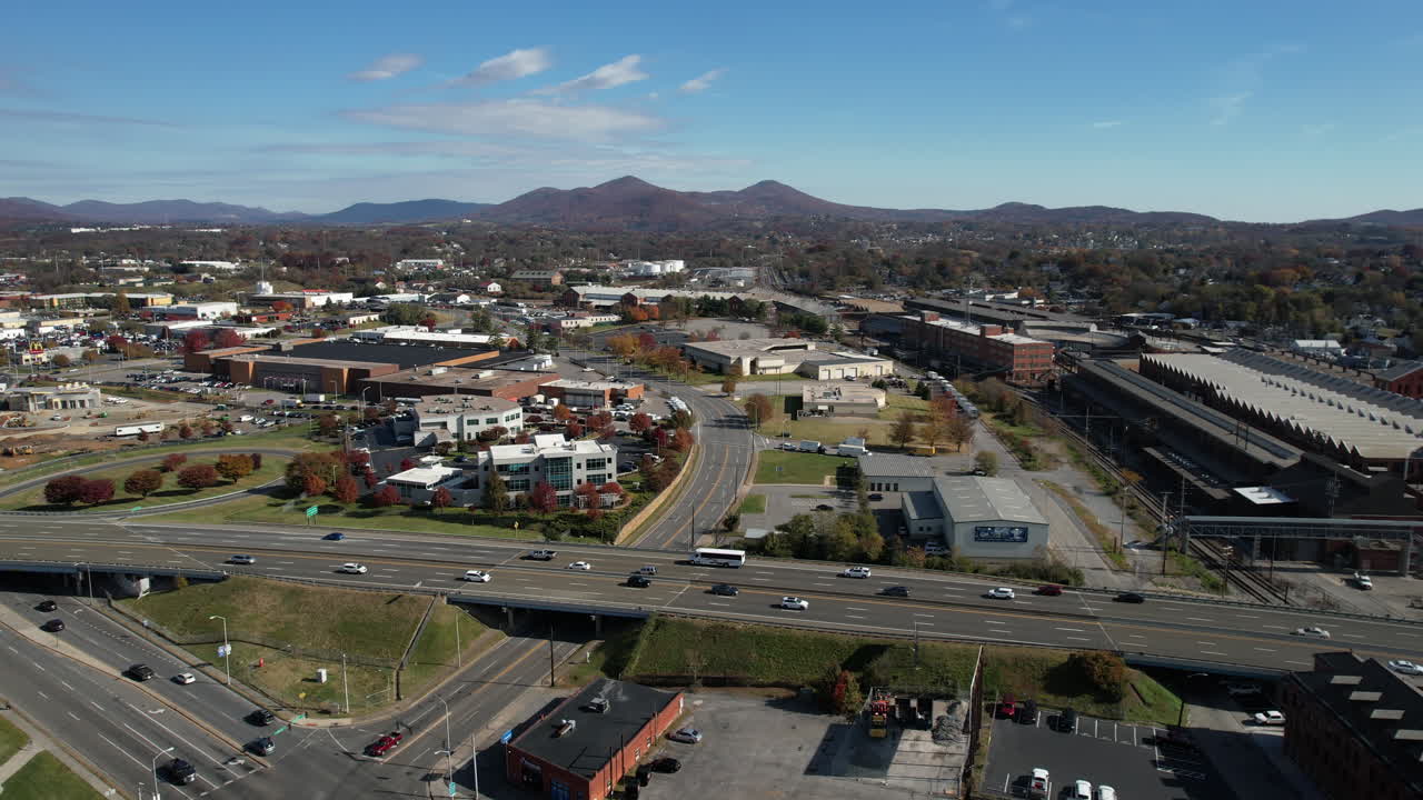 Aerial view of traffic on Interstate highway passing through Roanoke city, Virginia USA, cars and neighborhood buildings, drone shot