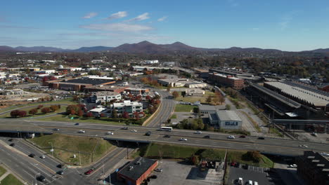 aerial view of traffic on interstate highway passing through roanoke city, virginia usa, cars and neighborhood buildings, drone shot