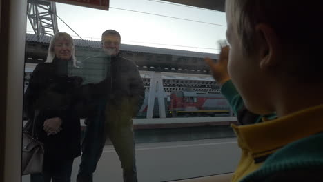 slow motion in saint-petersburg russia little boy from the train window waving to the grandparents who stand on the platform