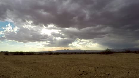 Stormy-clouds-rolling-over-Mojave-Desert-with-sun-shining-through,-Time-lapse