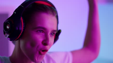 Happy-woman-celebrating-victory-in-neon-room-closeup.-Smiling-girl-take-headset