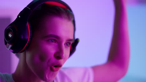 happy woman celebrating victory in neon room closeup. smiling girl take headset