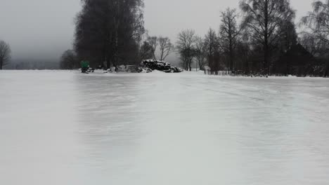 flying above frozen field with ice layer, person in green jacket stand